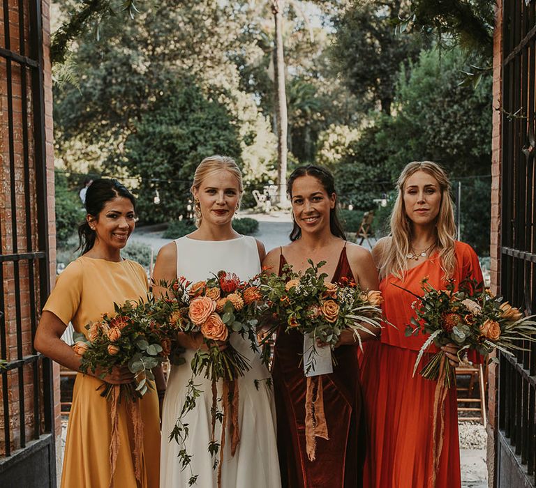 Bride in high neck wedding dress with bridesmaid dresses with yellow, orange, and red autumn colours