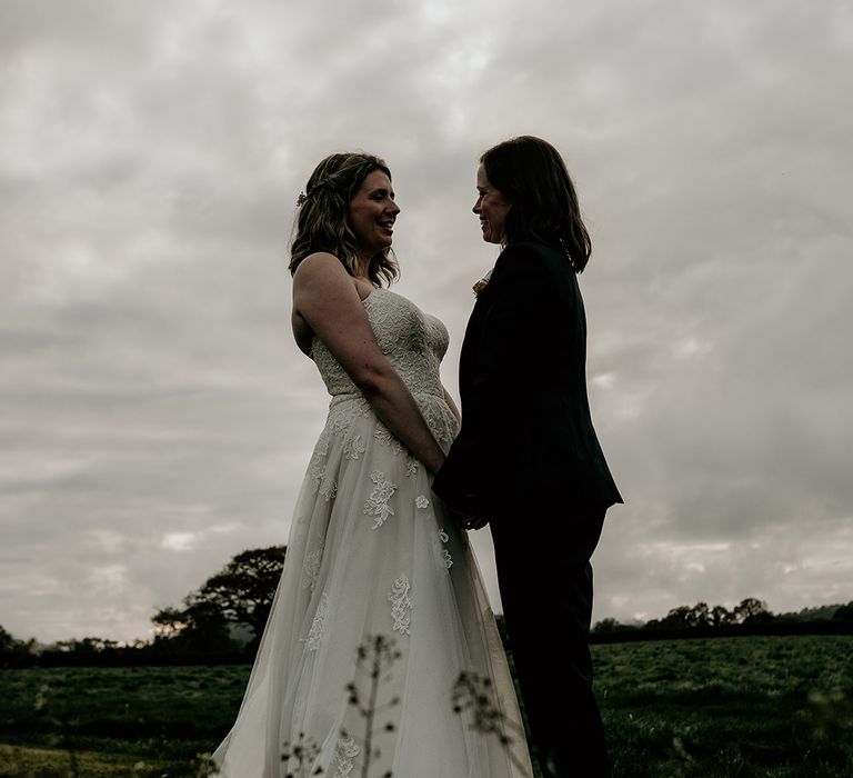 brides portrait in a field at Stanford farm wedding wearing a strapless lace wedding dress and navy suit 