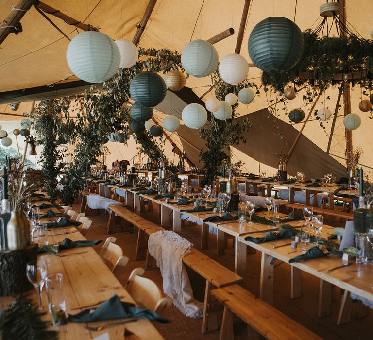 Tipi wedding venue decorated with green and gold paper lampshades, green foliage and green tablescapes