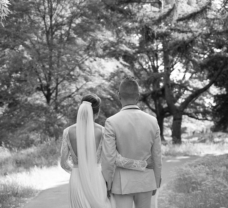 bride in a low back wedding dress with lace long sleeves embracing her groom 