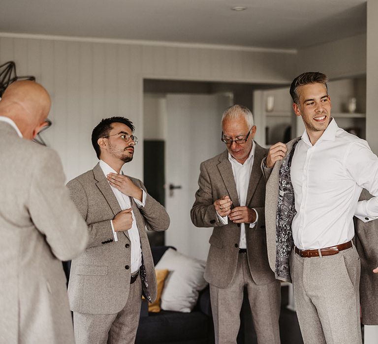 Groomsmen get ready together on the morning of the wedding wearing stone coloured suits 