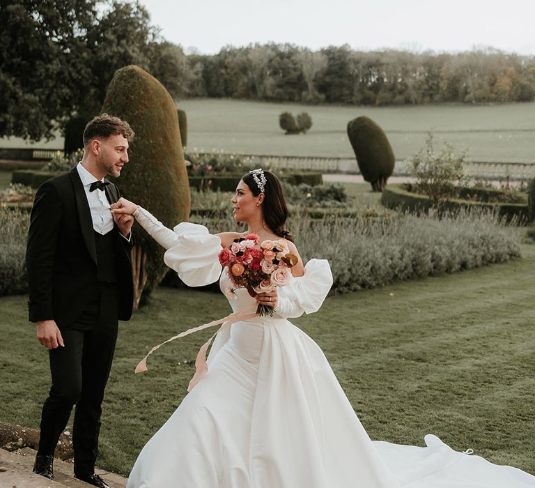 Bride in puff sleeve wedding dress with groom in black tuxedo walking around the grounds at Prestwold Hall 