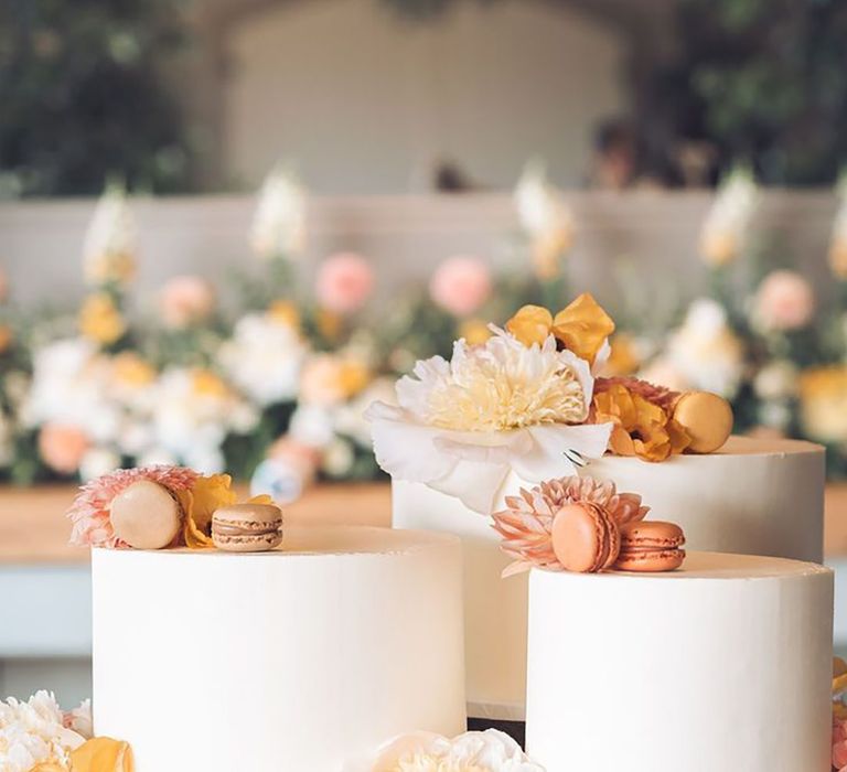 Wedding cakes decorated with yellow flowers and macarons with neutral flowers and macarons 