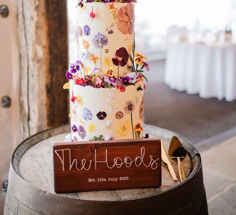 Tall three tier buttercream wedding cake with pressed wildflowers and topped with edible flowers for summer wedding 