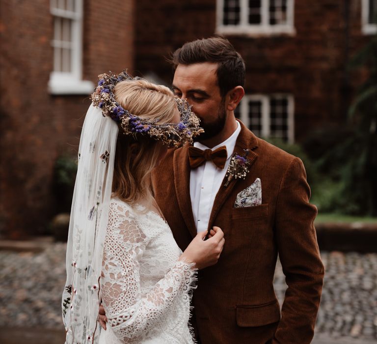 Groom kissing his brides head in a lace wedding dress