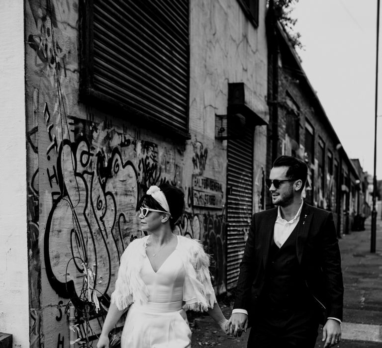 Bride and groom holding hands walking through the Liverpool streets 