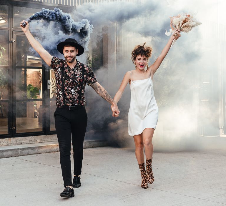 Bride in slip wedding dress with leopard print boots and groom in patterned shirt and hat 