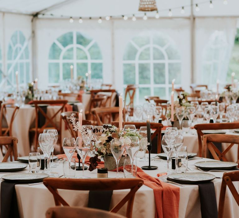 Round wedding table with brown, neutral and rustic orange wedding decor and details 