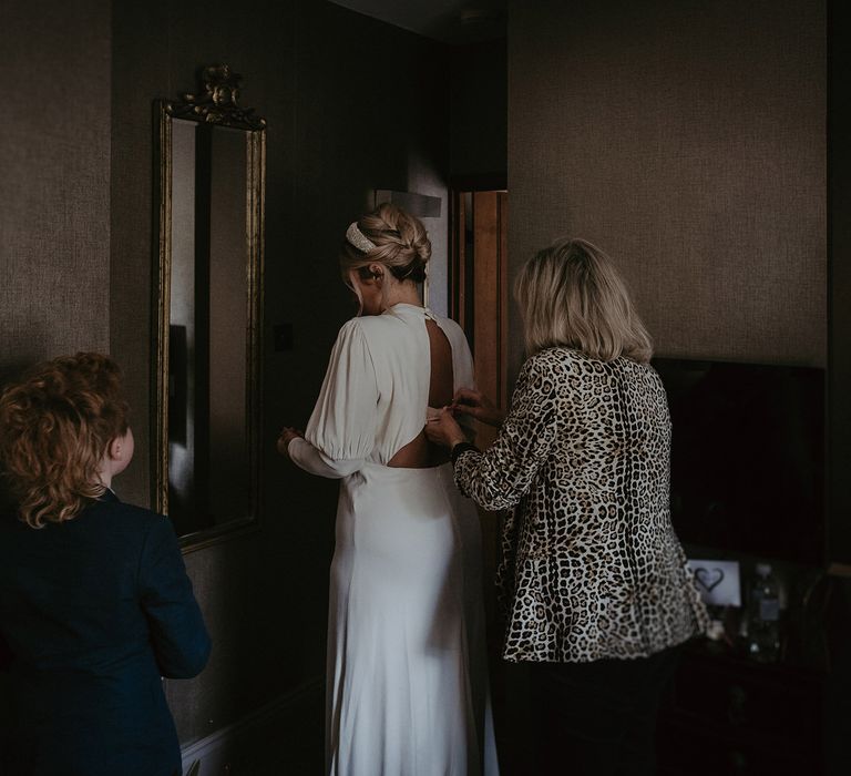 Bride on the wedding morning having her dress buttoned up 