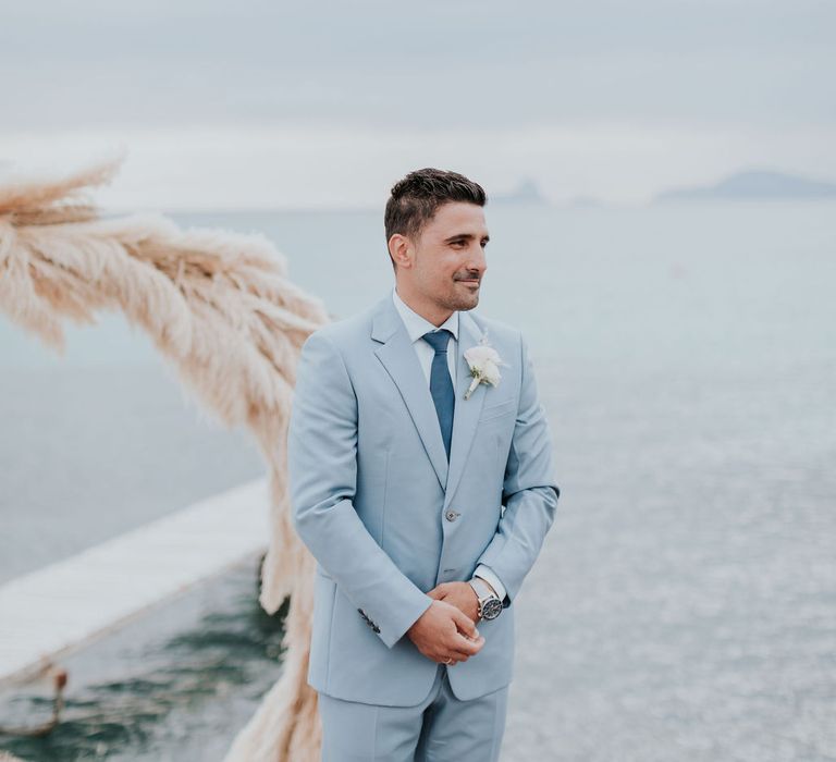 Groom in blue wedding suit waits for bride