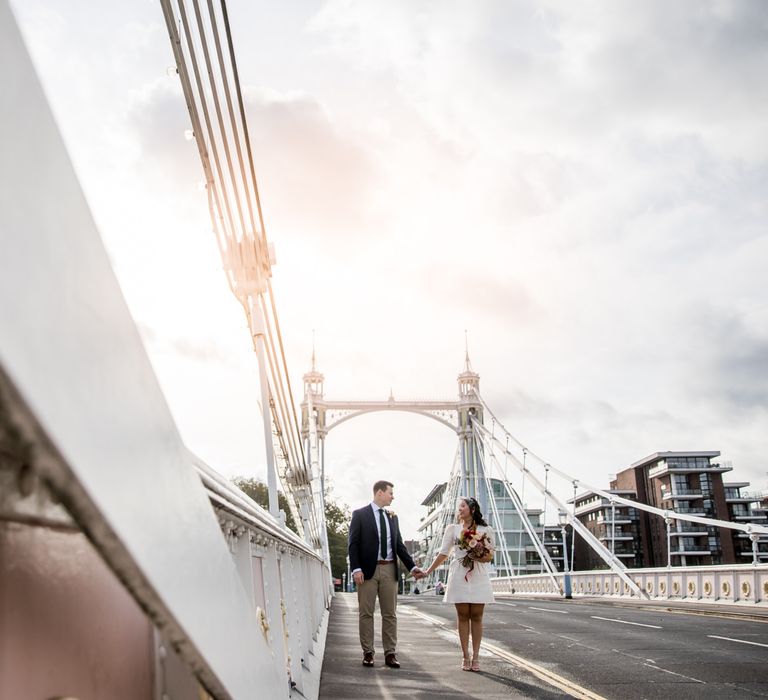 Portrait of the bride in a registry wedding dress and groom in beige trousers with navy blazer on Albert Bridge