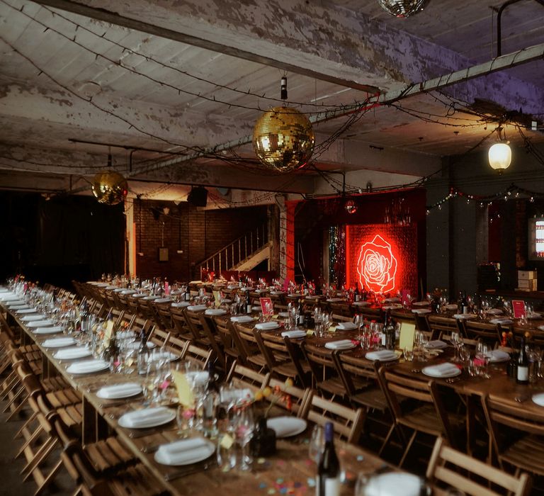 Wedding reception with long trestle wooden tables and rose neon sign 