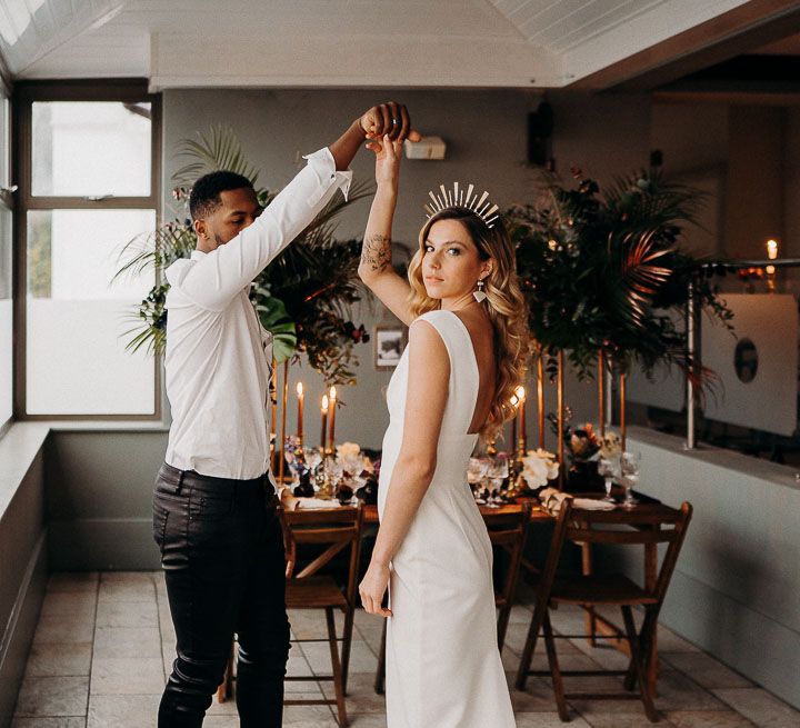 Groom in leather trousers and white shirt twirling his bride around in a fitted Sarah Seven wedding dress 