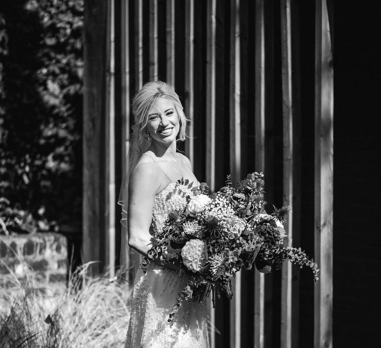 Bride stands in black & white image with homemade bouquet