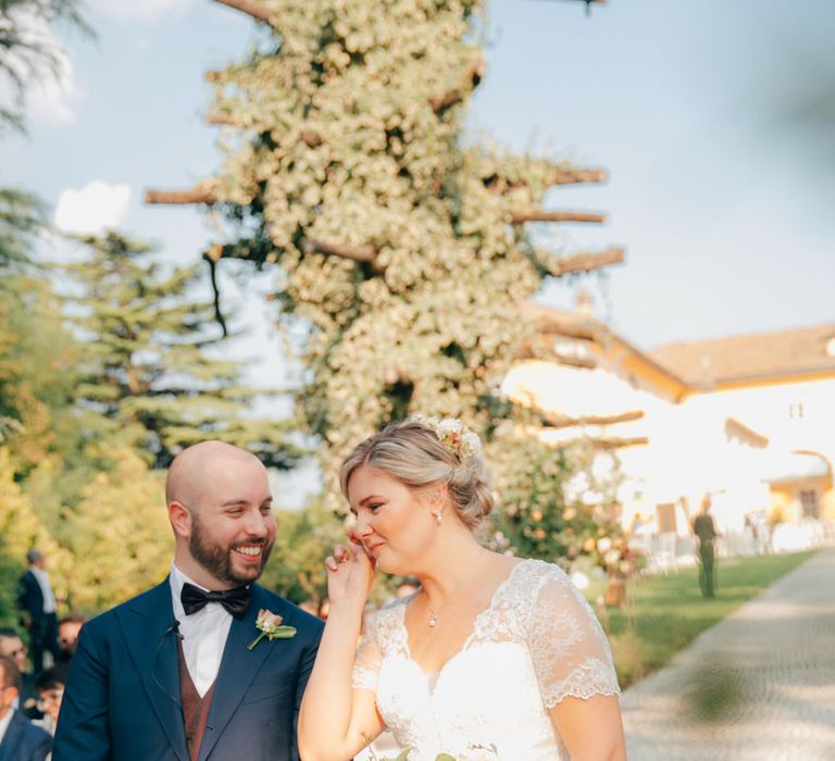 The bride and groom standing beside each other at the bottom of the aisle, the bride is wiping her cheek