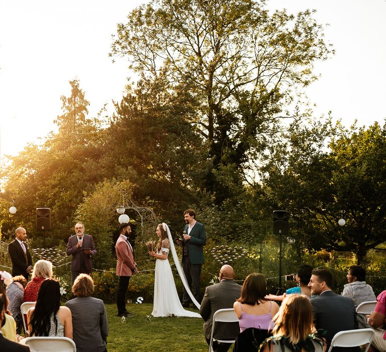 Sunlight streams through the trees during wedding ceremony outdoors