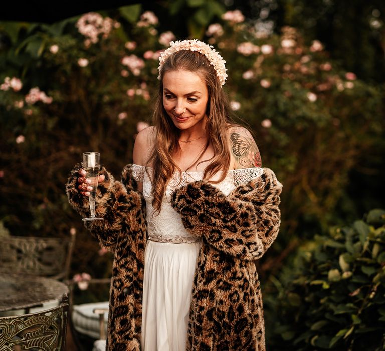 Bride wears furry leopard print jacket whilst holding champagne 