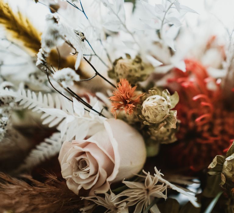 Autumnal floral bouquet tied with white ribbon and filled with white and orange blooms