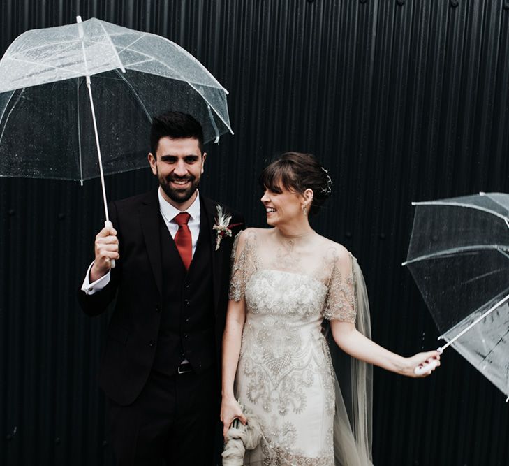 A bride and groom play with umbrellas during their wedding portraits.