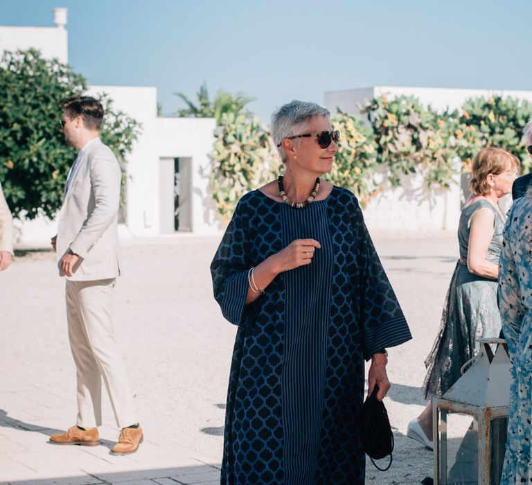 Wedding guest wearing a patterned smock dress and sunglasses for outdoor Italian wedding