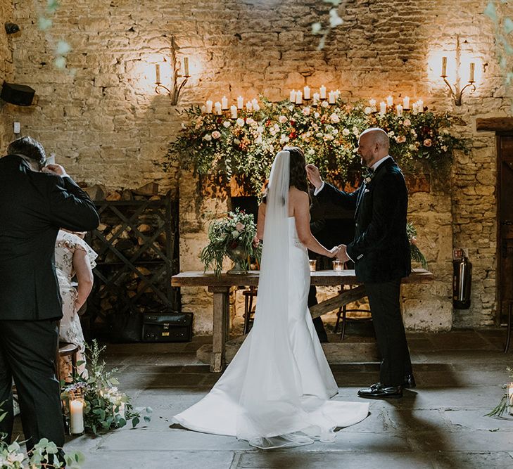 Wedding ceremony in front of Cripps Barns fireplace decorated with natural wedding flowers 