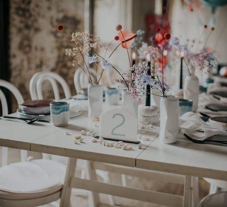 Pastel wedding flower stems decorating the all white table with an acrylic table name sign 