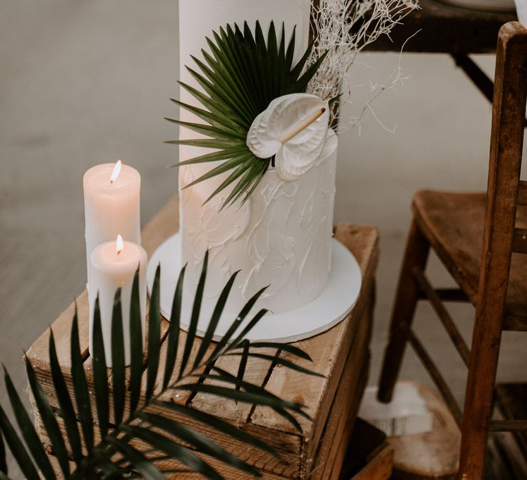 Two tier white wedding cake with palm leaf and white anthurium flower decoration