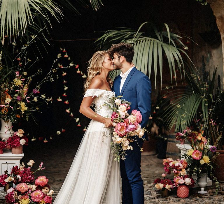 Bride and groom at finca wedding in Spain surrounded by pink florals and palm trees