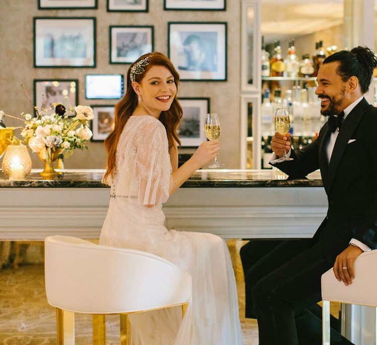 Bride in an embellished Eliza Jane Howell Paloma dress sitting at the bar at Grantley Hall wedding venue with her groom in a dinner jacket 