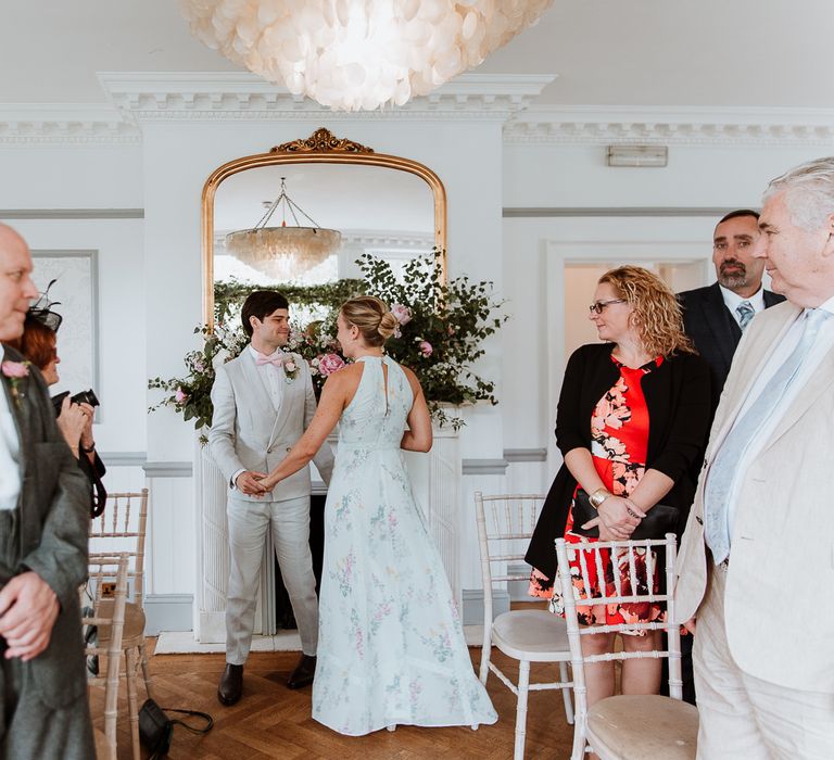 Bride & groom look lovingly at one another during wedding ceremony as guests watch