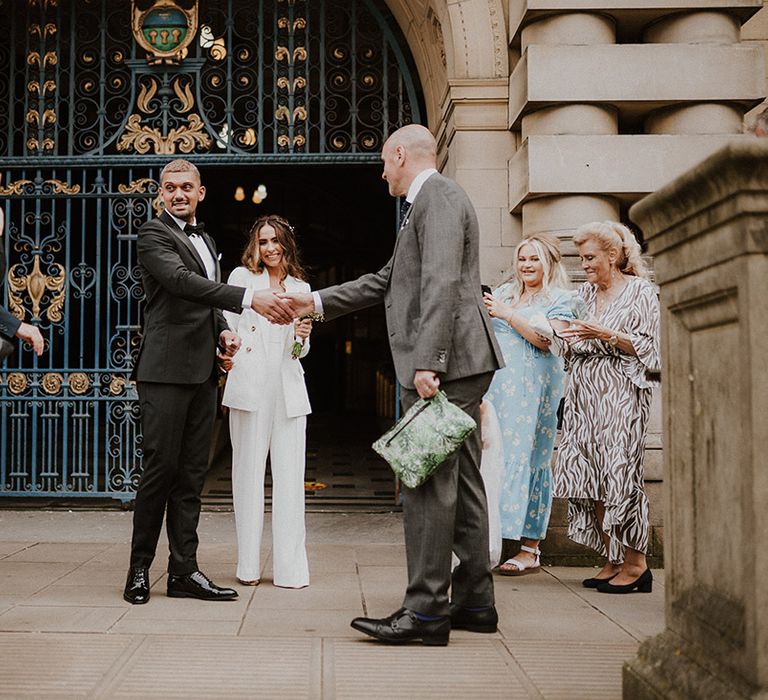 Groom shaking hands with guest outside his Sheffield registry office wedding 