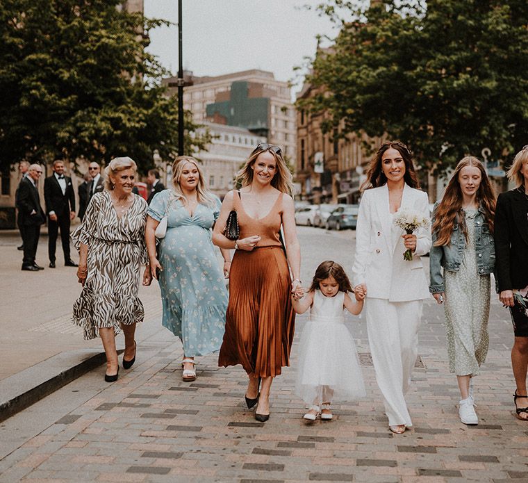 Bride in a white bridal suit and female guests walking through the streets of Sheffield