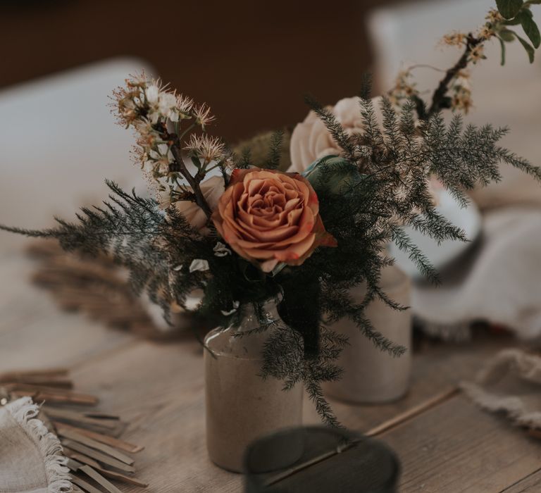 Muted pink and orange rose wedding flowers in ink wells 