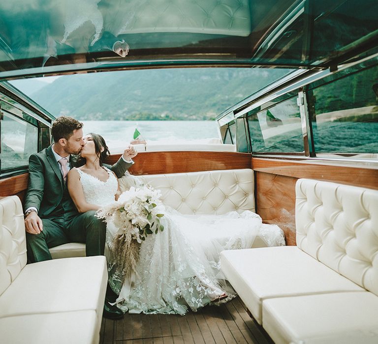 Bride & groom lean back on boat as they sail across Lake Como for elopement wedding