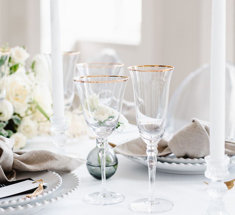 Three gold rimmed wine glasses are the ficus of a black and white wedding tablescape.