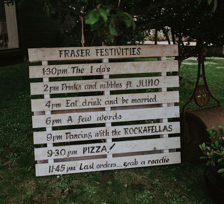 White wooden pallet wedding order of the day sign outside at Idle of Wight wedding with macrame wedding decor