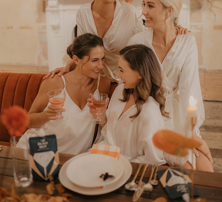 Bridesmaids in satin slips and getting ready robes drinking cocktails on the morning of the wedding 