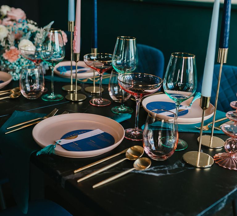 Pink and teal wedding table decor with coloured plates, glassware and flowers 