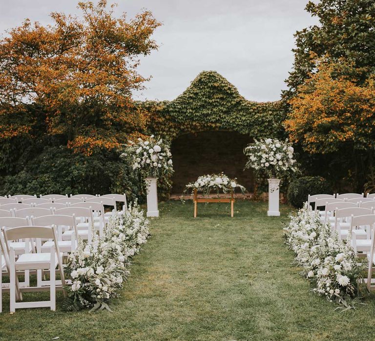 White wooden chairs, green and white flowers and outdoor aisle for outdoor wedding ceremony at Notley Abbey