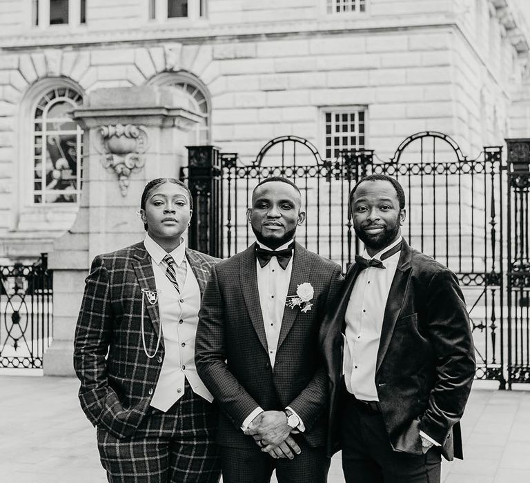 Groom stands with his groomsmen who wear black tie on wedding day