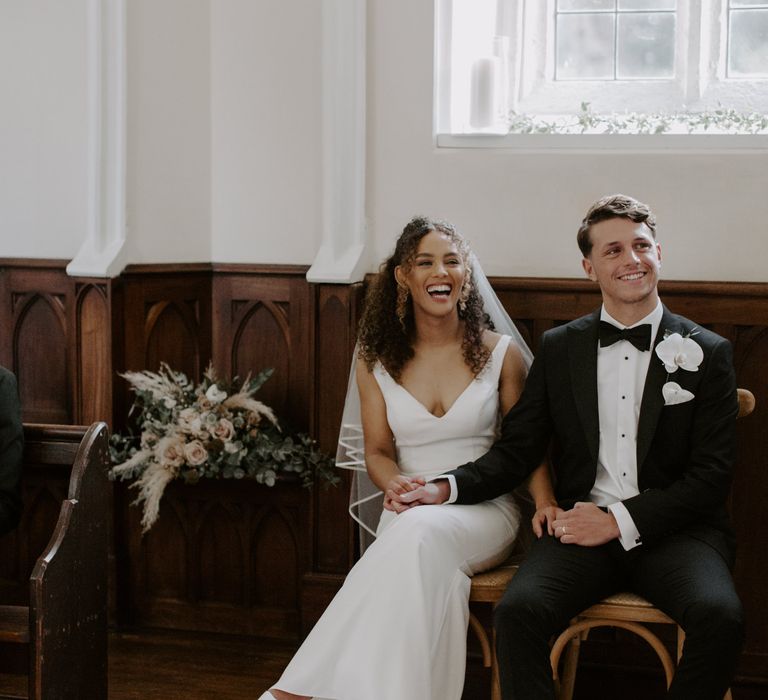 Bride & groom laugh and smile on their wedding day during Christian ceremony