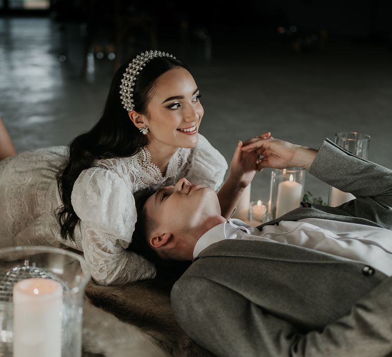 Bride wears pearl head crown on her wedding day as she lays with her groom 