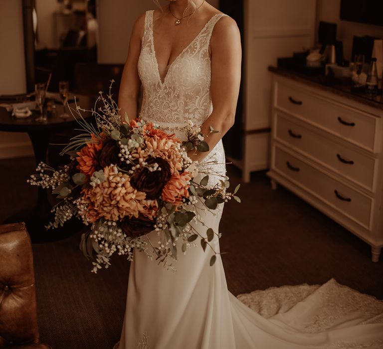 Blonde bride holds Autumnal floral bouquet