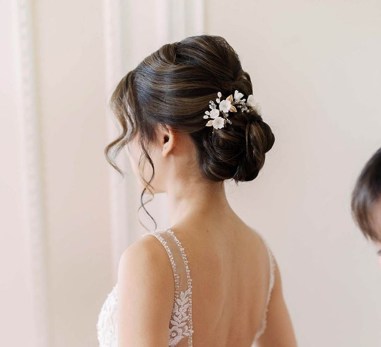 Bride has her dress done up on the morning of her wedding day and wears her black hair in a low bun