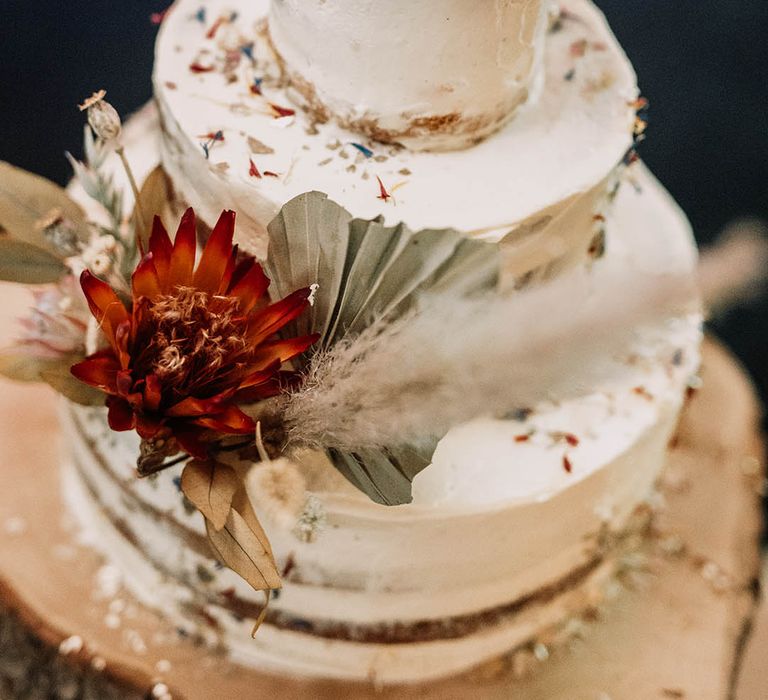 Three tier wedding cake complete with white frosting and bright floral decor 