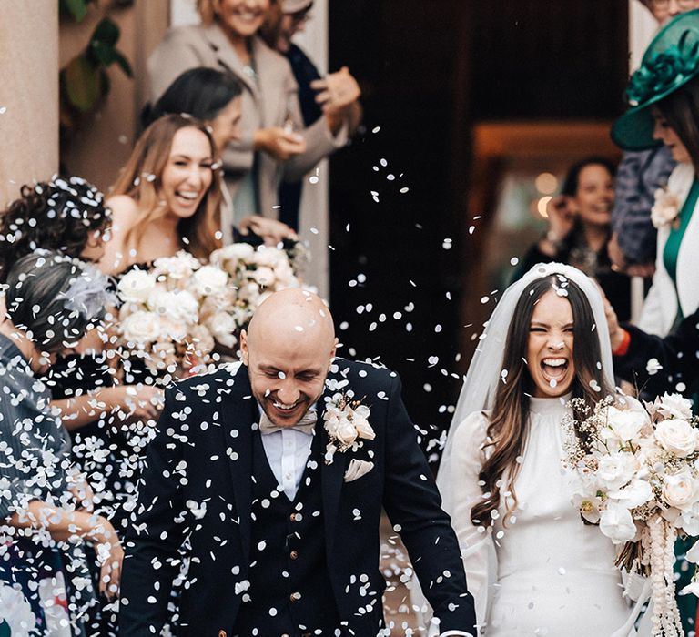 White confetti moment on the steps at Iscoyd Park with bride in a long sleeve wedding dress and groom a black three-piece suit 