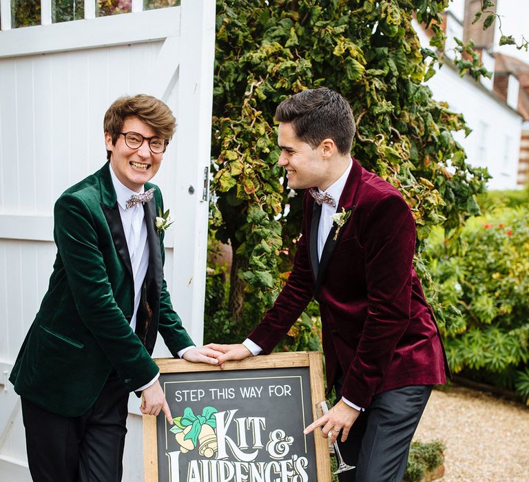 Grooms pose together with black board welcome sign personalised with names and dates