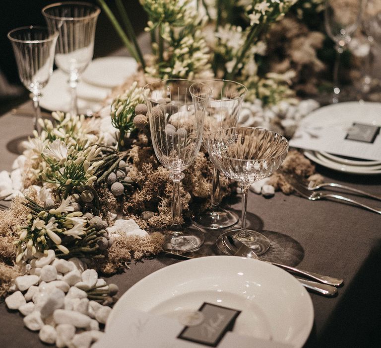 elegant wedding table decor with white and green floral centrepieces and glass goblets and saucers 