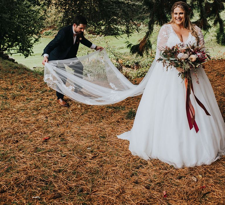 Autumn wedding with bride in a princess wedding dress with embroidered lace wedding train holding a protea wedding bouquet 