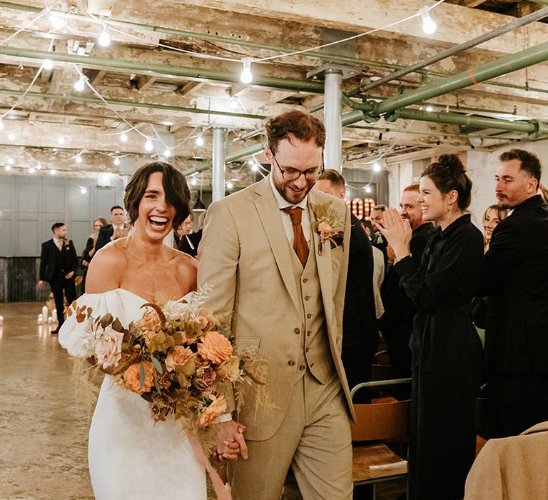 Bride and groom exit their wedding ceremony at industrial venue 